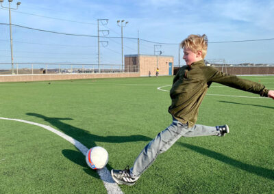A little boy kicking a ball on the rooftop soccer field at the Princeton Club.