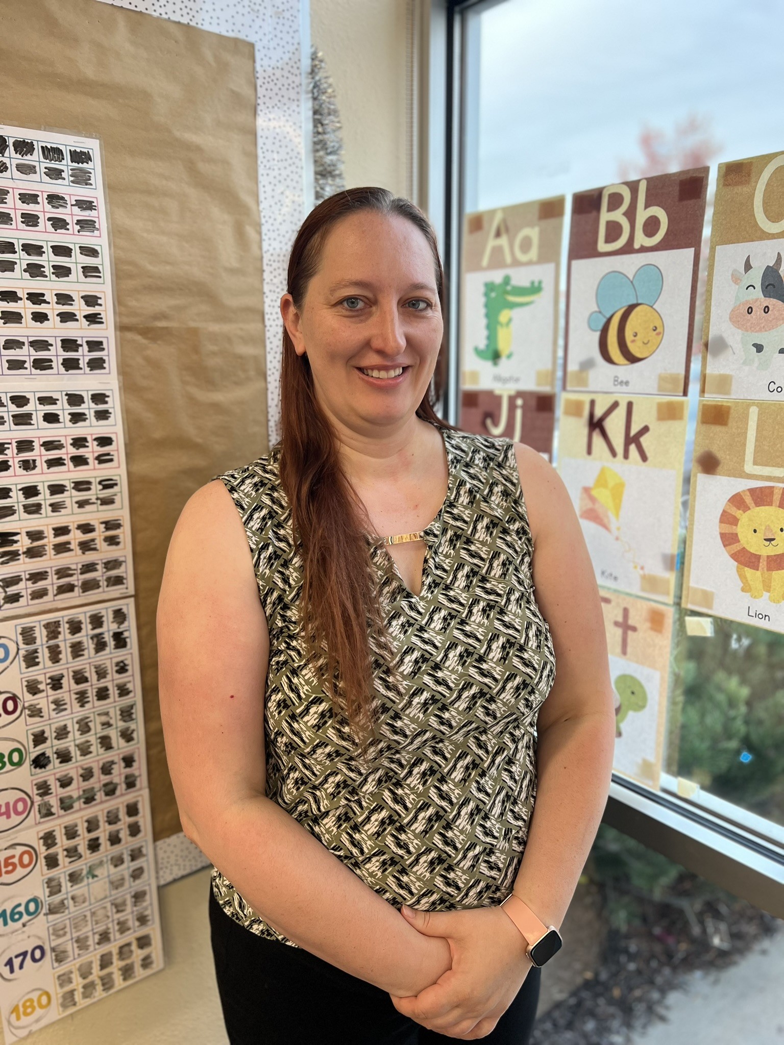 A portrait-style picture of Pam standing in a classroom and smiling at the camera.